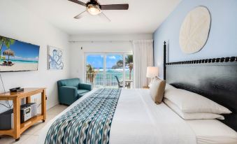 a bedroom with a large bed , blue walls , and a view of the ocean through a sliding glass door at Wyndham Reef Resort Grand Cayman