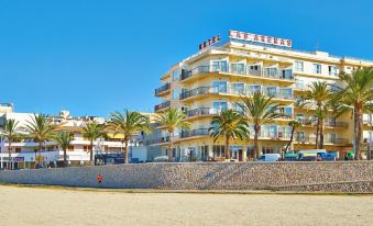 a beach scene with a large hotel building on the sandy shore , surrounded by palm trees at Hotel Las Arenas