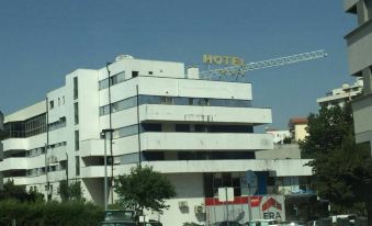 "a modern building with the name "" hotel "" in yellow letters , surrounded by other buildings and cars on a street" at Hotel Navarras