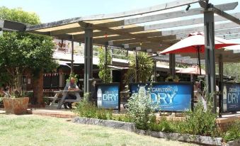 an outdoor dining area at a restaurant , with several tables and chairs set up for guests at Bonnie Doon Hotel