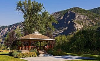 a wooden gazebo surrounded by green grass and trees , with a mountain in the background at Rocky Point Ranch
