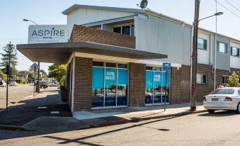 "a modern building with a sign that reads "" aspire "" and a car parked outside , under a clear blue sky" at Aspire Mayfield