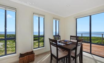 a dining room with a table and chairs , along with a view of the ocean at Seaspray
