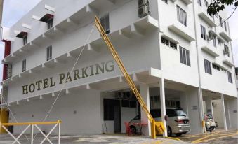 a parking lot with a car parked in front of a building , and another car parked nearby at Royale Hotel Batu Gajah