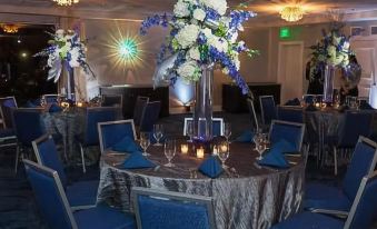 a formal dining room with multiple tables set for a banquet , each adorned with blue tablecloths and decorated with floral centerpieces at Delray Sands Resort