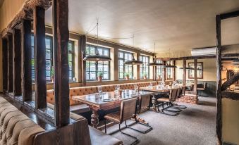 a large dining room with wooden tables and chairs , along with a bar in the background at The Cricketers Clavering