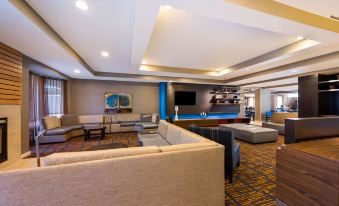 a large room with a couch , chairs , and a bar is shown in the image at Sonesta Select Detroit Novi