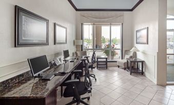 a room with multiple computer workstations , each equipped with a computer and a laptop , near large windows at Best Western High Road Inn