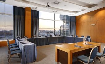 a conference room with wooden tables , chairs , and a large window overlooking a city view at Hotel Diamante