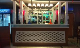 a modern bar with white walls , wooden columns , and multiple bottles of liquor on display at Hotel Taj