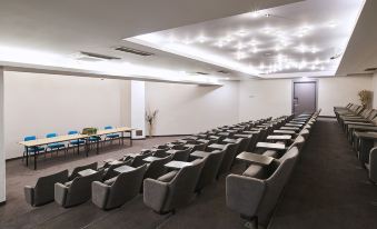 a large , empty conference room with rows of gray chairs and a few tables set for meetings at Aminess Lume Hotel