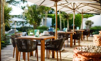 an outdoor dining area with several tables and chairs under umbrellas , providing shade for guests at The Atlantic Hotel