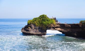 a large rock formation juts out into the ocean , with a small building perched atop it at favehotel Langko Mataram - Lombok