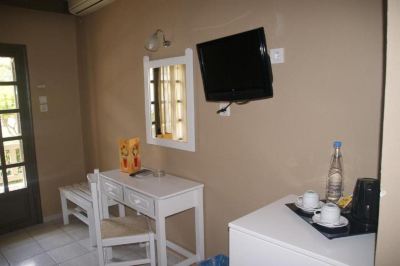 a small room with a tv mounted on the wall , a desk , and a chair at Valley Village