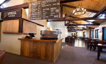 a coffee shop with a wooden counter and chairs , along with a menu board on the wall at The Park Hotel Ruapehu