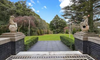 a lush green garden with a path leading to the entrance , surrounded by trees and bushes at The Robertson Hotel