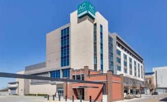 a modern office building with a large sign on the side , surrounded by trees and other buildings at AC Hotel Cincinnati at Liberty Center