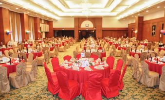 a large banquet hall with multiple tables covered in red tablecloths and chairs arranged for a formal event at Mulia Hotel