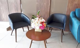 There are two chairs and a table with flowers on it in the CBD 2-bedroom at Hotin Inn