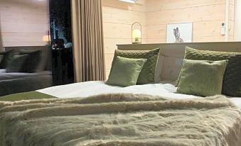 a bedroom with a large bed , green pillows , and a fur blanket on top of the bed at Arctic Skylight Lodge