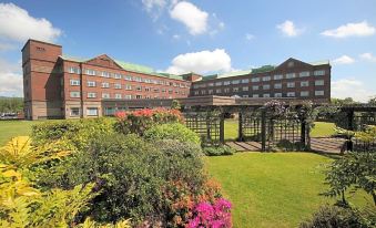 a large hotel with a garden and flowers , under a clear blue sky with clouds at The Golden Jubilee Hotel