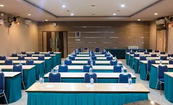 a conference room with rows of tables and chairs , each table having a blue seat and a white table at Grand Krakatau Hotel Serang