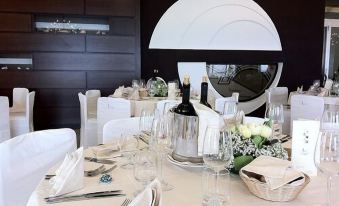 a well - decorated dining room with a white tablecloth , wine glasses , and a bottle of wine on the table at Hotel la Lucertola