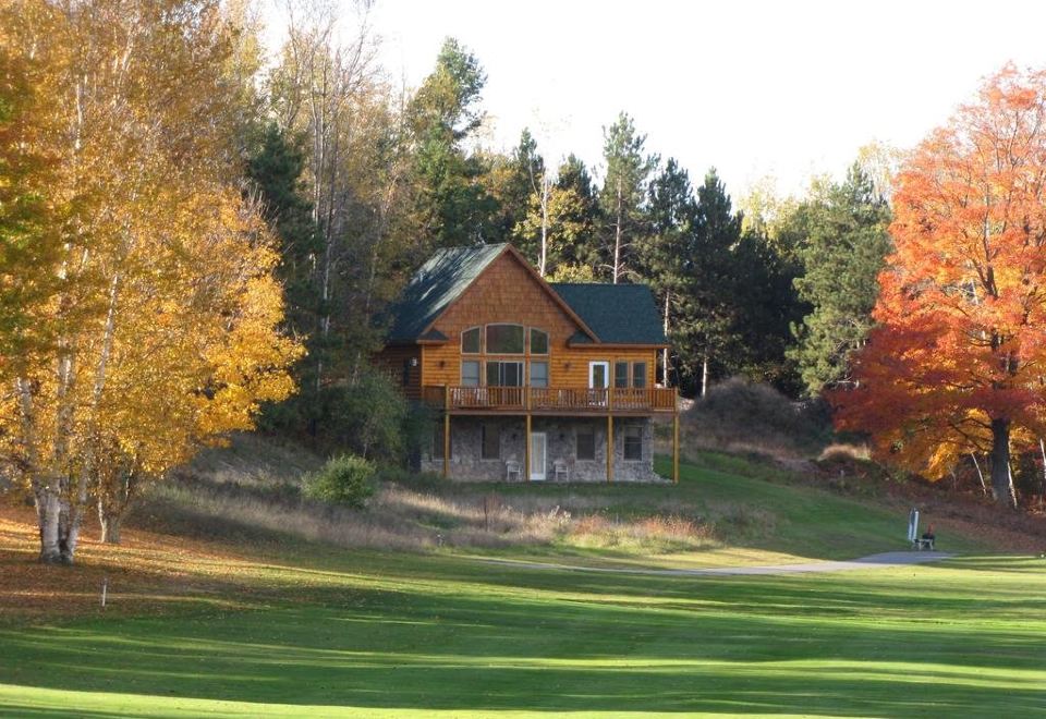 a house with a wooden exterior is surrounded by trees and grass on a golf course at Agaming Golf Resort