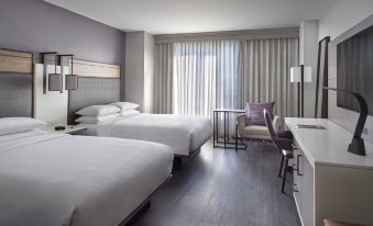 a hotel room with two beds , a desk , and a window , all decorated in white and purple colors at Raleigh Marriott City Center