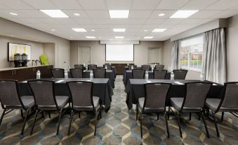 a large conference room with multiple rows of chairs arranged in a semicircle , and a projector mounted on the wall at Residence Inn Saddle River