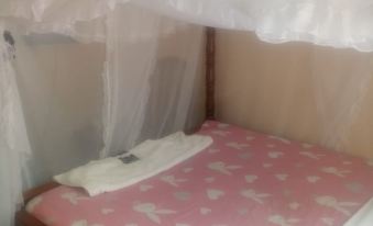 a bed with a pink and white butterfly patterned bedspread , under a white canopy , has two pillows and a white towel on it at The Reeds Hotel