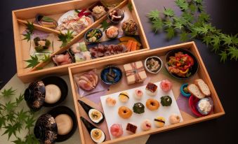 a wooden tray filled with a variety of appetizers and desserts , placed on a dining table at Yufuin Hotel Shuhokan