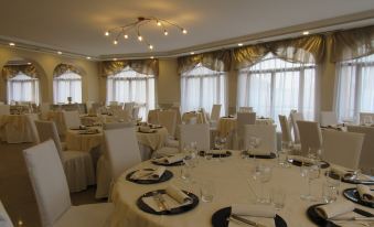 a well - decorated banquet hall with multiple round tables and chairs set up for a formal event at Green Hotel