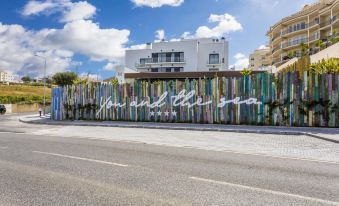 "a long , colorful wall with a large sign that says "" hill club "" is in front of a white building" at You and the Sea