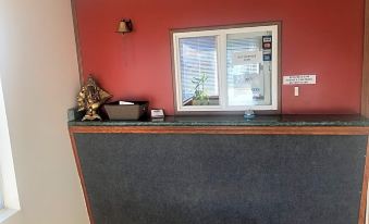 a modern office reception area with a red wall , black countertop , and a window on the right side at Oxford Inn