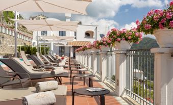 a balcony overlooking the ocean , with several lounge chairs and umbrellas set up for relaxation at Villa Piedimonte
