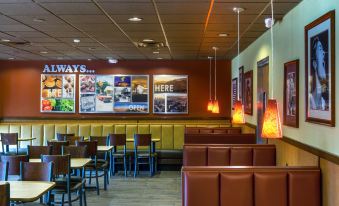 "a modern fast food restaurant interior with brown booths , a sign that says "" always here "", and colorful decorations" at Best Western Plus Carriage Inn