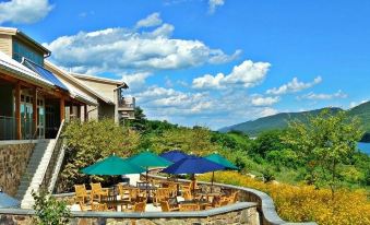 a patio area with multiple umbrellas , chairs , and tables set up for outdoor dining , surrounded by trees and mountains at Nature Inn at Bald Eagle