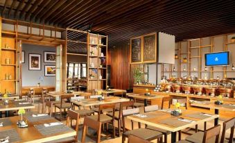 a dining room with wooden tables and chairs arranged for a group of people to enjoy a meal together at BATIQA Hotel Lampung