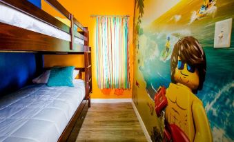 a bunk bed with a beach theme , decorated with an orange and blue theme , including a large mural of a person wearing sunglasses at Legoland Beach Retreat