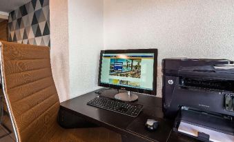 a black desk with a computer monitor , keyboard , and mouse on it , along with a chair in the background at Best Western Plus Executive Suites