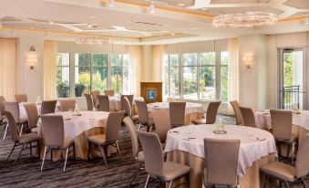 a large , well - lit banquet hall with multiple round tables and chairs arranged for a formal event at The Hotel Landing