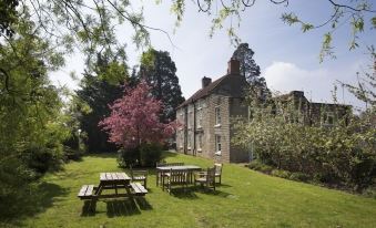 a large stone house surrounded by a lush green lawn , with several picnic tables in the area at The Coachman Inn