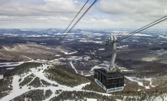 aerial view of a snow - covered ski resort with a gondola lift in the sky , surrounded by mountains at Jay Peak Resort