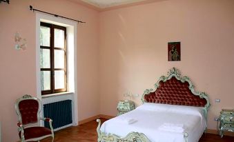 a large bed with a white headboard and red pillows is in a room with pink walls at Villa Luisa