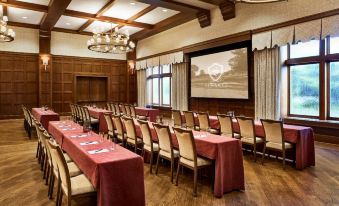 a conference room set up for a meeting , with multiple chairs arranged in rows and a projector screen on the wall at The Sewanee Inn