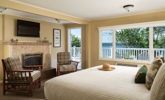 a cozy bedroom with a large bed , a fireplace , and a window overlooking the ocean at Silver Birches Resort