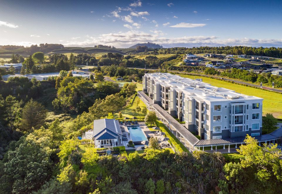 a bird 's eye view of a modern apartment complex with buildings , trees , and mountains in the background at Hilton Lake Taupo