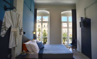a well - lit bedroom with a large bed , blue curtains , and a balcony view of the city at Habit