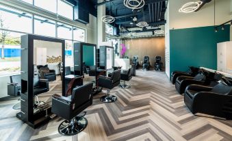 a modern hair salon with black leather chairs and couches arranged in a zigzag pattern at Aloft Seattle Redmond